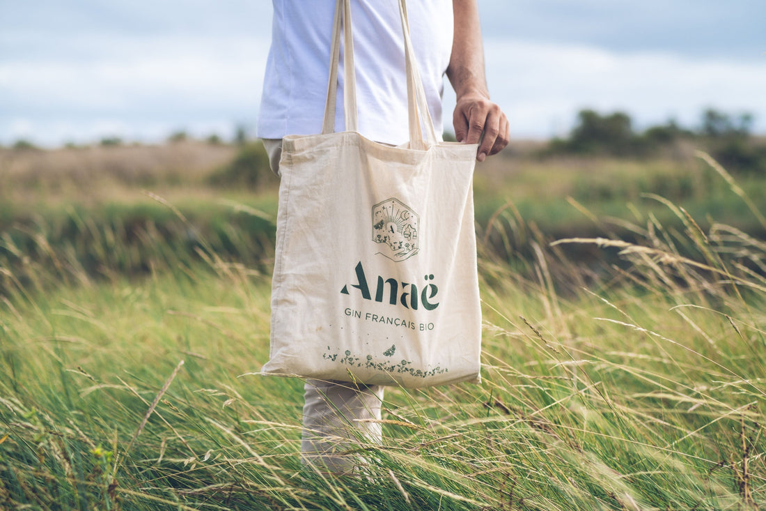 Person carrying a custom printed canvas tote bag in a grassy field