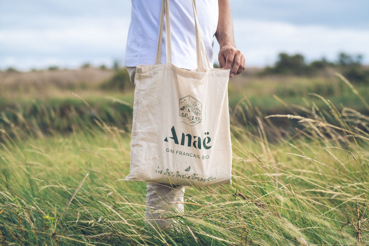 Person carrying a custom printed canvas tote bag in a grassy field